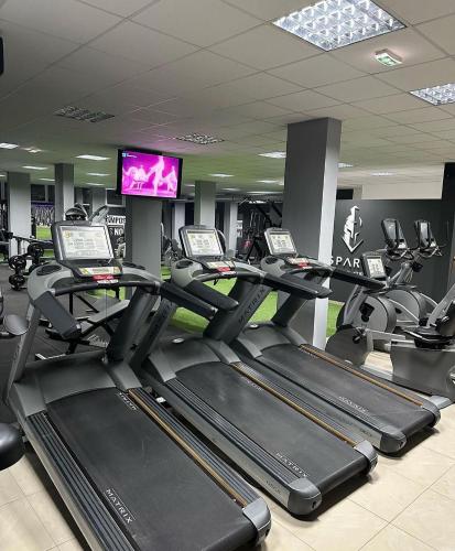 a gym with several tread machines and a flat screen tv at Beta House Apartments in Zaječar