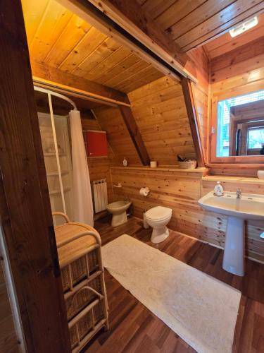 uma casa de banho em madeira com um lavatório e um WC em Chalet Natura la taverna dei 3 porcellini em Cavaliere