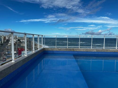 a swimming pool with a view of the ocean at Lindo Studio em frente a praia in Salvador