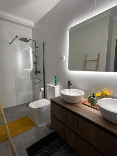 a bathroom with two sinks and a toilet and a mirror at Quinta do Rio Alva and Glamping Lodges in Mouronho