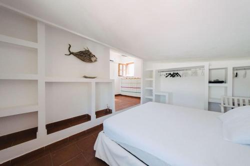a bedroom with a white bed and white shelves at Appartamento / villa parghelia con piscina in Parghelia