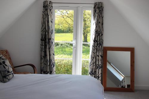 a bedroom with a bed and a mirror and a window at The Old Workshop - a cosy country retreat in Gloucester