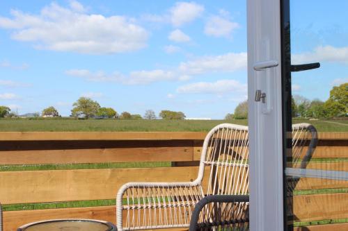 a bench on a porch with a view of a field at The Old Workshop - a cosy country retreat in Gloucester