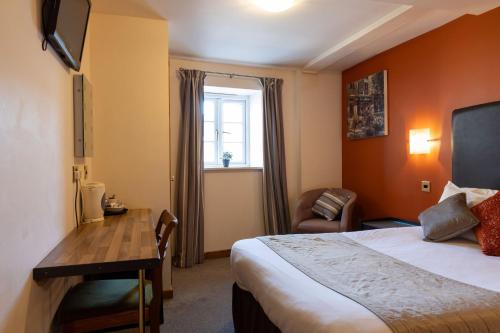 um quarto de hotel com uma cama, uma secretária e uma janela em The Warehouse em Yeovil