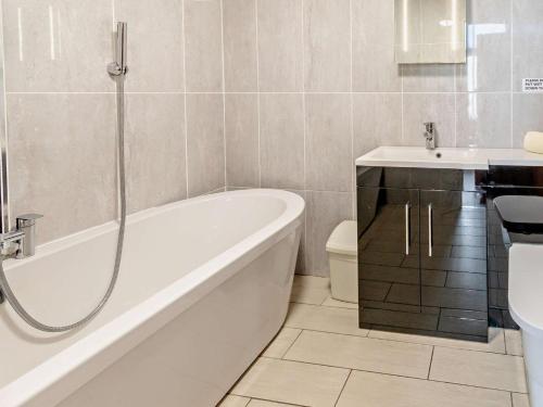 a bathroom with a tub and a sink and a toilet at 3 Bed in Tenby 60757 in Tenby