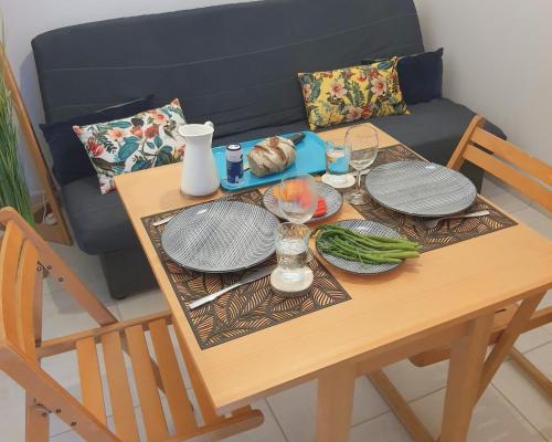 a wooden table with plates and glasses on it at ღ Le cocon Montilien - Confortable T2 avec Wifi in Montélimar