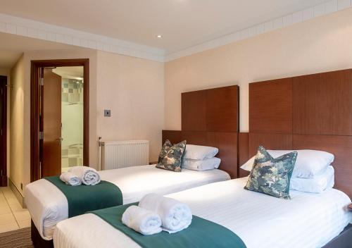 a hotel room with two beds with towels on them at Thatchers, BW Signature Collection in East Horsley