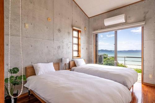 two beds in a room with a large window at ヴィラ カエルラ in Nago