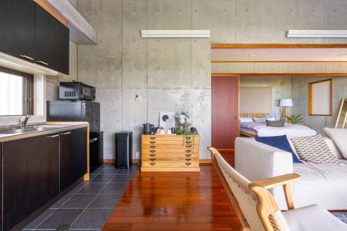 a room with a kitchen and a bedroom with two beds at ヴィラ カエルラ in Nago