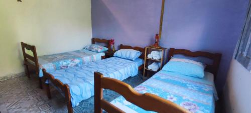 three beds in a room with purple walls at Eco Hostel Lunar in Soure