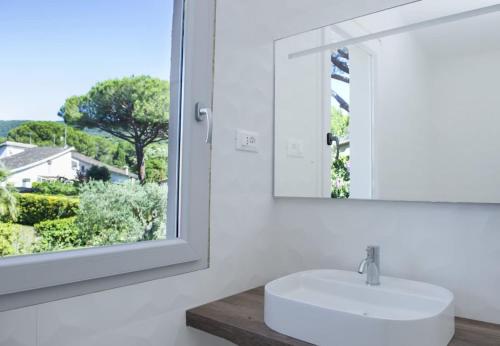 W łazience znajduje się biała umywalka i lustro. w obiekcie Villaflair - Villa Bounganville w mieście Punta Ala