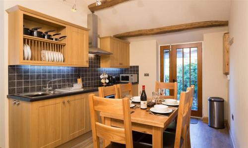 a kitchen with a wooden table with chairs and a sink at Abbots Reading Mews 1 in Lake Side
