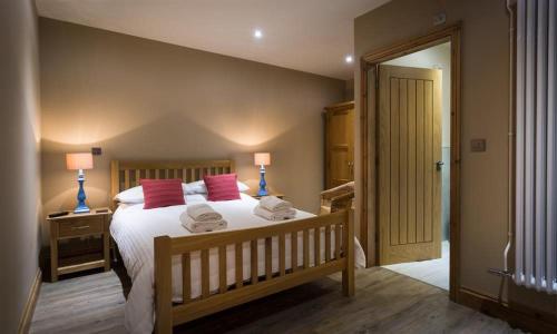 a bedroom with a large bed with red pillows at Abbots Reading Mews 1 in Lake Side