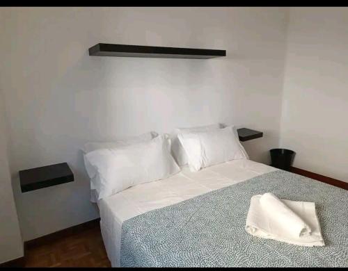 um quarto com uma cama com lençóis brancos e almofadas em luminosa habitación en vallecas em Madri