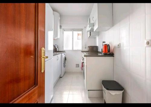a small kitchen with white appliances and a wooden door at luminosa habitación en vallecas in Madrid