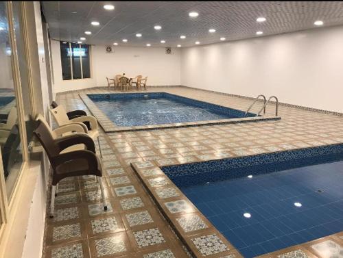 a large swimming pool in a room with chairs and tables at شاليه غزال GHAZAL CHALET in Nimrān