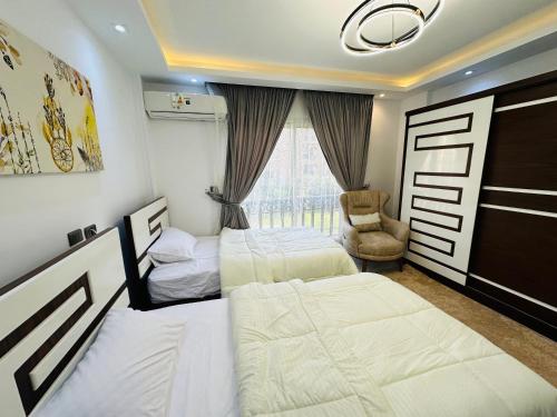 MadinatyMadinaty Hotel Apartment的有两张床和一把椅子的卧室