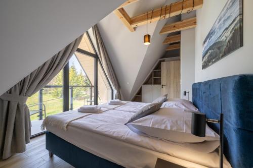 a bedroom with a large bed and a large window at Silent Mountain Residence in Bukowina Tatrzańska
