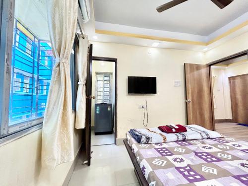 a bedroom with a bed and a tv on the wall at Stylish 1RK Serviced Apartment in Tollygunge in Kolkata