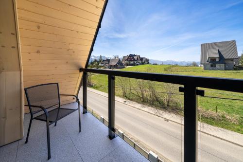 a chair on a balcony with a view of a road at Silent Mountain in Bukowina Tatrzańska