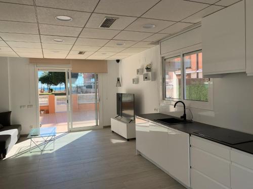 een keuken met witte kasten en een woonkamer bij Apartamento sol y playa in Calafell