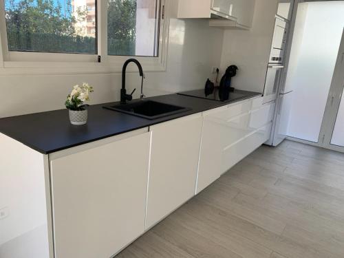 een keuken met witte kasten en een zwart aanrecht bij Apartamento sol y playa in Calafell