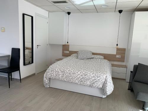 een slaapkamer met een bed, een bureau en een stoel bij Apartamento sol y playa in Calafell