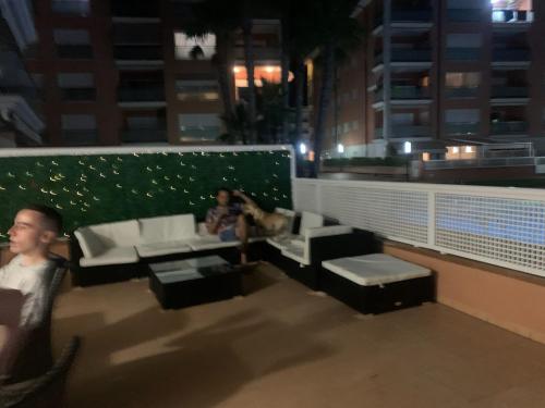 een paar mensen die 's nachts op een balkon zitten bij Apartamento sol y playa in Calafell