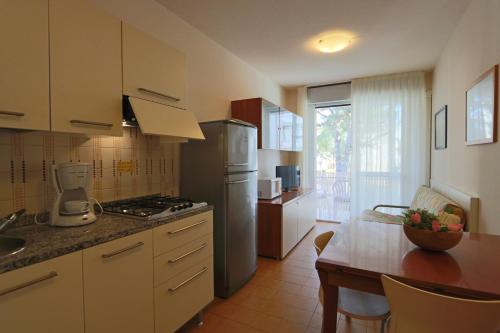 a kitchen with a table and a refrigerator and a stove at Appartamenti Erica in Bibione