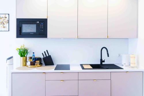 Una cocina blanca con fregadero y microondas. en Apartament Kulturalny, en Sanok
