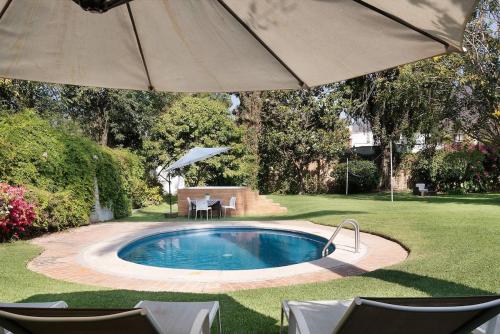 a swimming pool with an umbrella in a yard at Welcome to Villa Cristy 3-BR 3 5-WC in the La Floresta area in Ajijic