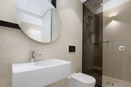 W łazience znajduje się umywalka, toaleta i lustro. w obiekcie Fawkner Apartment Bay-view 4 w Melbourne