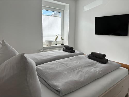 two white beds in a room with a flat screen tv at HeimatHafen & Meer in Sassnitz