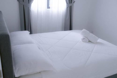 Una cama con sábanas blancas y una toalla. en LA CASABAYU HOMESTAY, en Kampung Dengkil