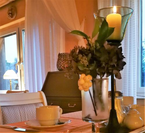 een tafel met een kaars en een vaas met bloemen bij Landhaus Martens in Bresewitz