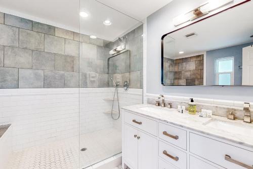 een badkamer met een douche, 2 wastafels en een spiegel bij Gecko Getaway in Fort Myers