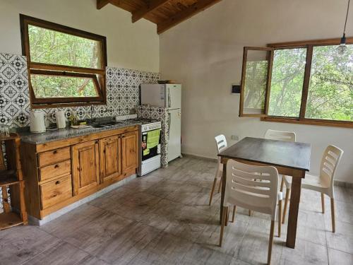 cocina con mesa, sillas y nevera en Las Casitas del Pozo en Villa General Belgrano