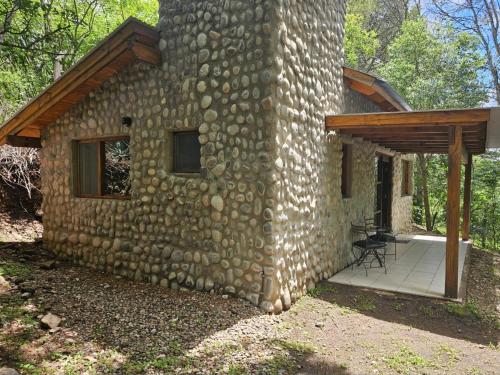 un edificio de piedra con porche y patio en Las Casitas del Pozo en Villa General Belgrano