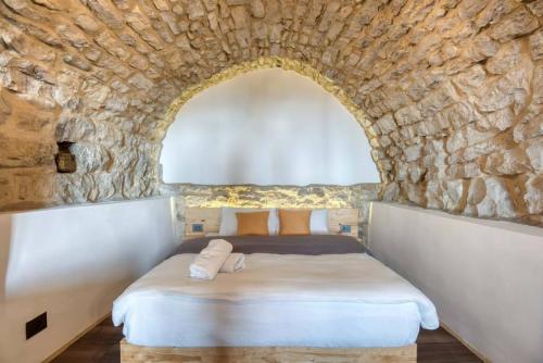 a bedroom with a bed in a stone wall at La Kava 1-BR Apt with Terrace in Ain Aar in Al ‘Aţshānah