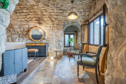 a room with a stone wall with chairs and a table at La Kava 1-BR Apt with Terrace in Ain Aar in Al ‘Aţshānah