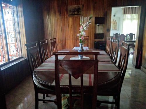 een eettafel met stoelen en een vaas met bloemen erop bij Maliga inn in Gampola