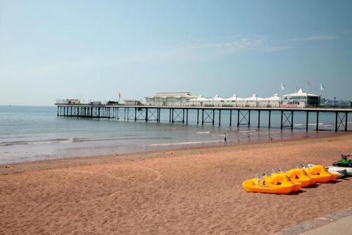 a group of yellow kayaks on a beach with a pier at Cambria Hotel in Paignton