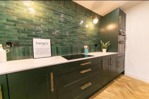 a kitchen with a sink and a green brick wall at Beautifully styled Home with Garden in Poulton le Fylde