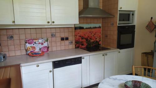 a kitchen with white cabinets and a painting on the wall at Maison paisible à Veyras avec piscine privée et vue montagne in Veyras