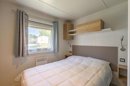 une petite chambre avec un lit et une fenêtre dans l'établissement Mh 169 Ronce les bains, à La Tremblade