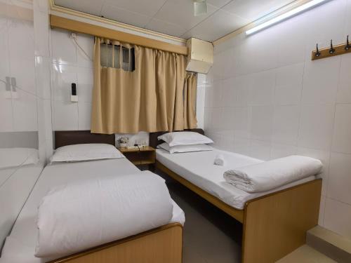 um pequeno quarto com 2 camas e uma janela em 香港太阳宾馆 em Hong Kong