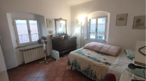 a bedroom with a bed and a dresser and windows at Il Nido di Paola in Carrara