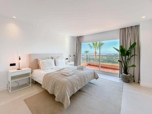 een witte slaapkamer met een groot bed en een groot raam bij HEATED ROOFTOP POOL PENTHOUSE VIEWS MAGNA MARBELLA in Marbella