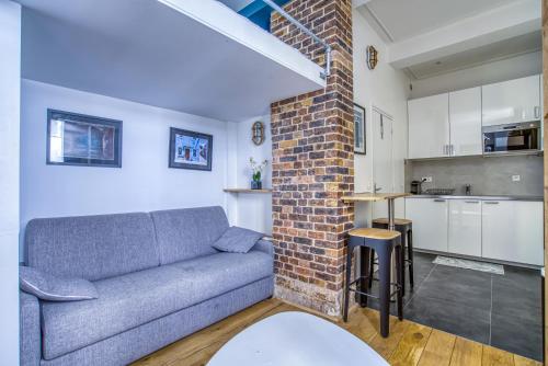 un salon avec un canapé et un mur de briques dans l'établissement Nemo, Studio avec mezzanine sur cour Porte Maillot, à Paris