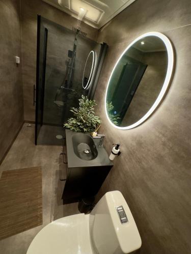 a bathroom with a toilet and a round mirror at Exotisk lägenhet/ Friparkering in Västerås
